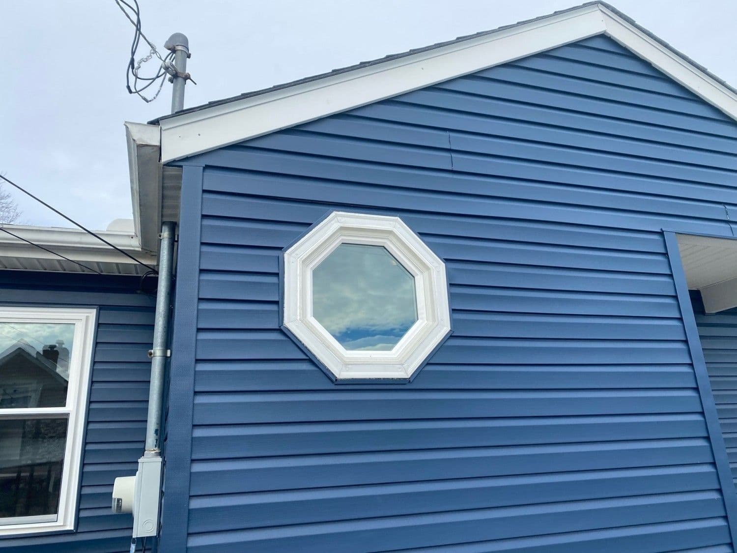 Blue house exterior with octagonal window and satellite dish mounted on roof